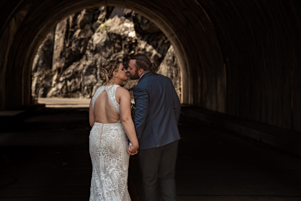 Couple in wedding attire going into a tunnel and kissing.