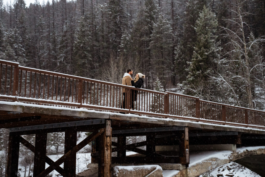 Engaged couple standing on Belton Bridge in Glacier NP.