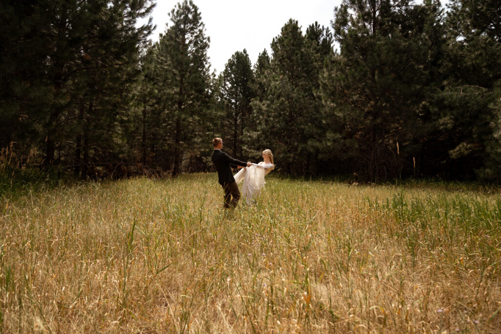 bride and groom spinning in field before elopement.