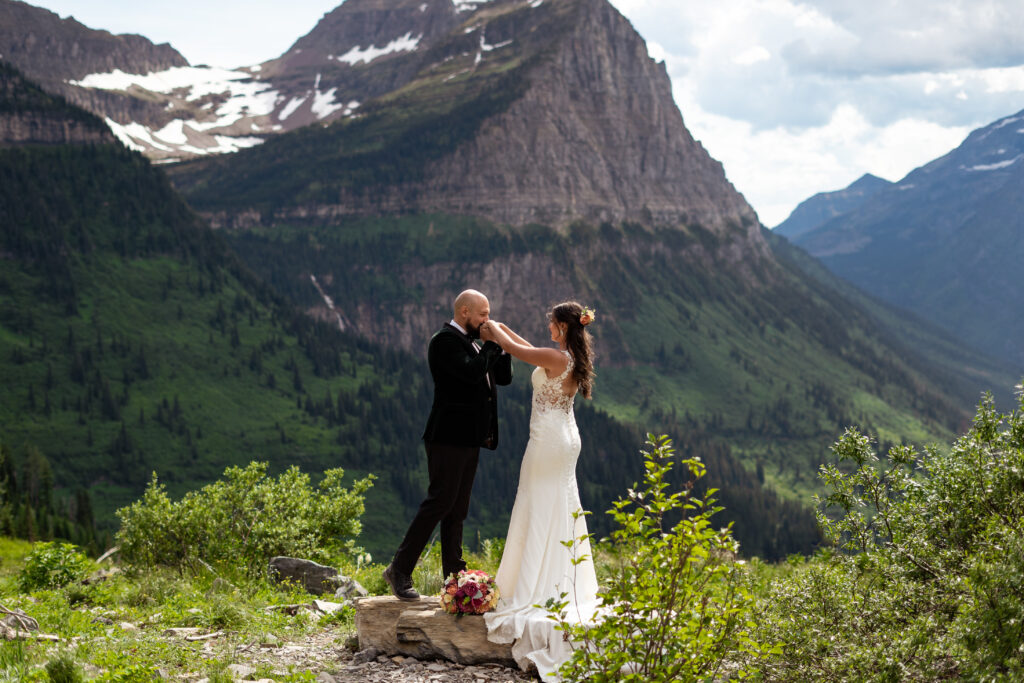 Groom kissing brides hands in Glacier National Park.